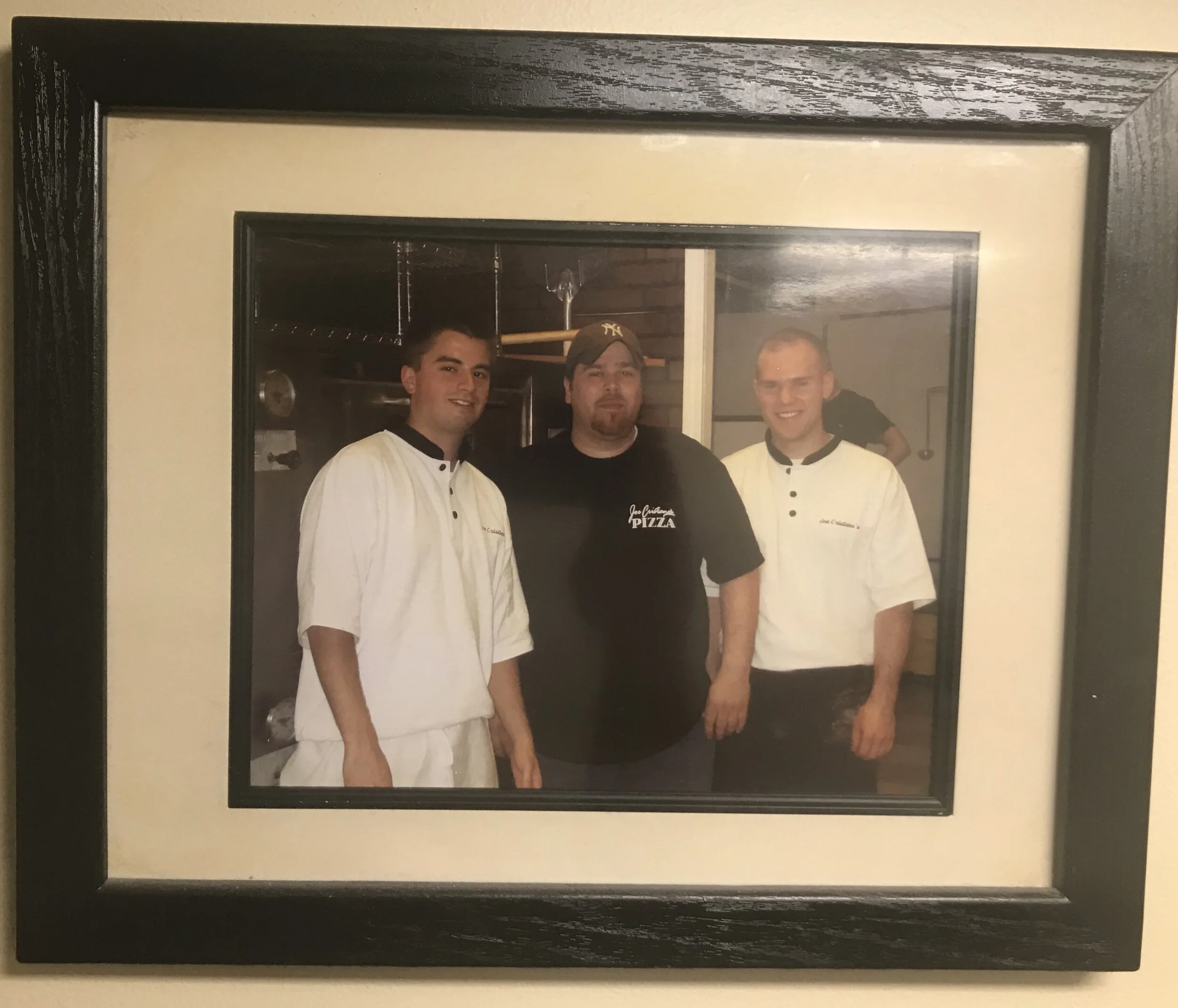 A framed photograph of three Joe Cristiano’s Pizza team members in the kitchen